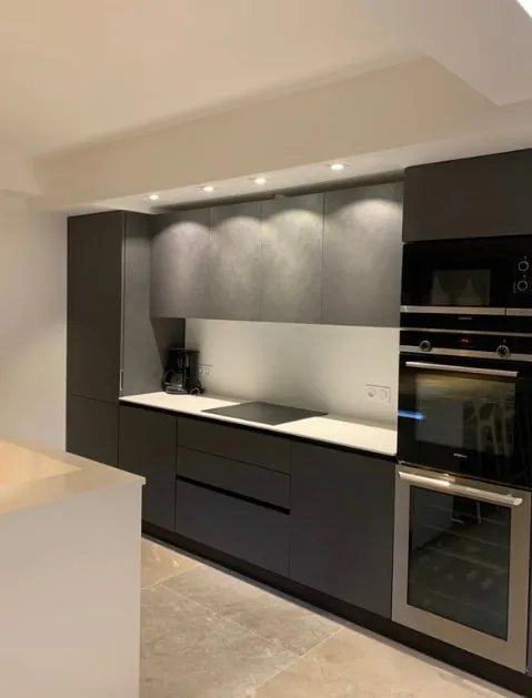 Cuisine équipée noire et plan de travail clair, appartement entièrement rénové à Nice