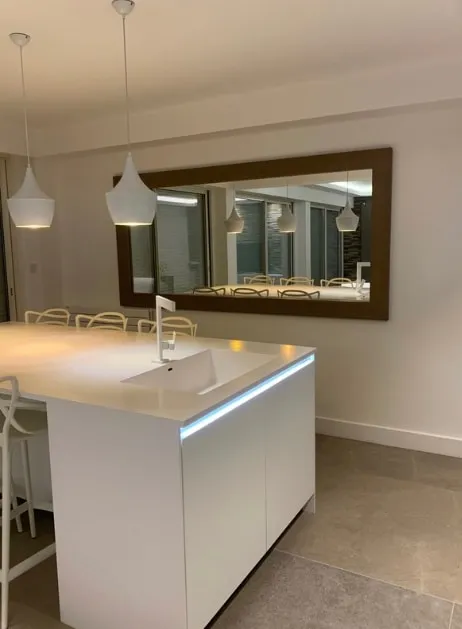 Îlot de cuisine éclairé et grand miroir, appartement niçois rénové