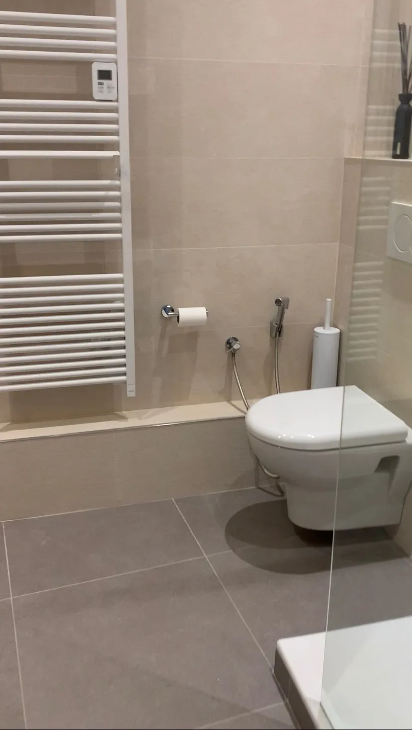 Salle de bain rénovée avec WC suspendu, sèche-serviettes et carrelage grand format